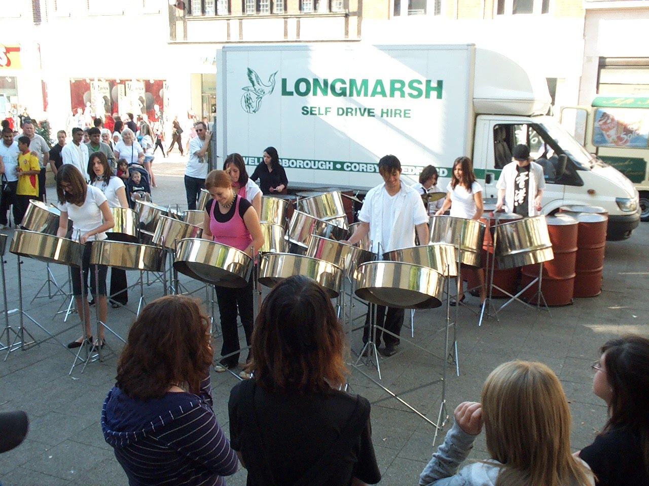 Students playing silver steel pans with mallets in classroom