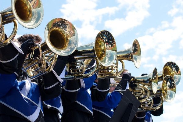 Bright daytime baritone horn section holding horns in sunshine