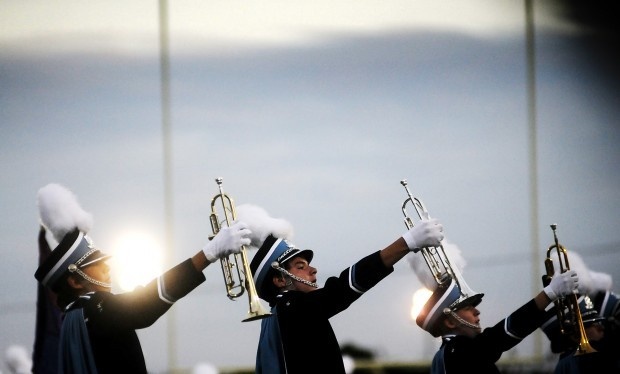 Nighttime trumpet line with horns angled skyward under lights