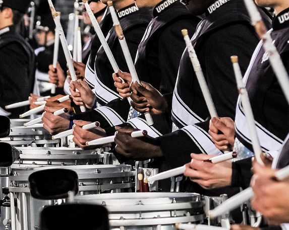 Tight snare drumline crop showing unison stick heights and rimshot preparation