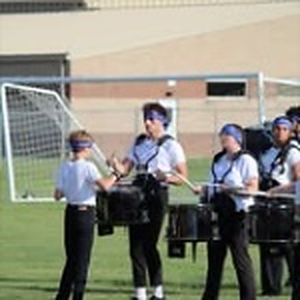 Lincolnview drumline students practicing on grass in white shirts and blue bandanas